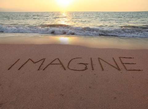 Photo of beautiful sandy seashore with the word Imagine written in the sand